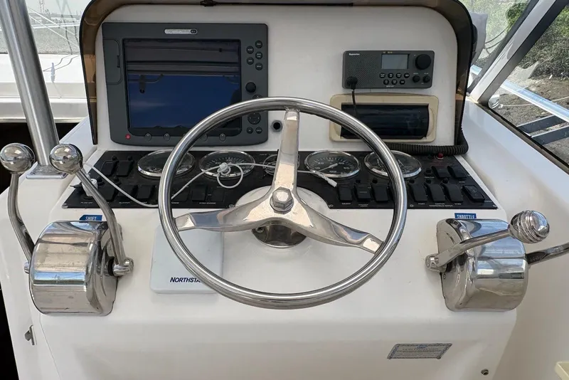 Slide: The Image of Control panel of a 2004 Luhrs 30 Open boat with steering wheel and navigation equipment. - 9