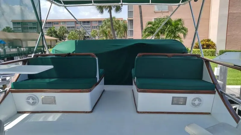 Slide: The Image of 1979 Universal Marine 41 boat deck with green seating and canopy, docked near buildings. - 2