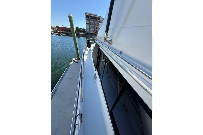 Slide: The Image of 1991 Californian 55 Cockpit Motor Yacht docked, showcasing sleek side view and marina backdrop. - 11