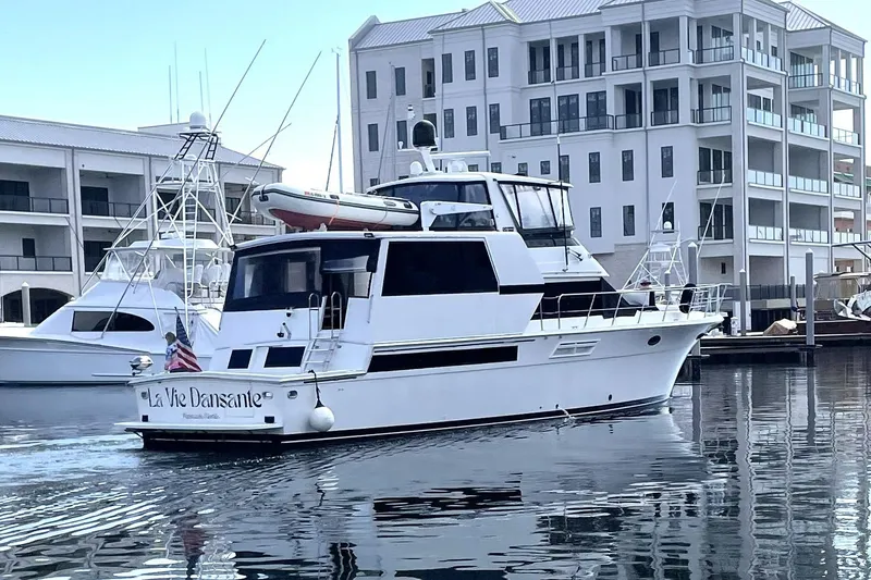 Slide: The Image of 1991 Californian 55 Cockpit Motor Yacht docked near modern buildings. - 2