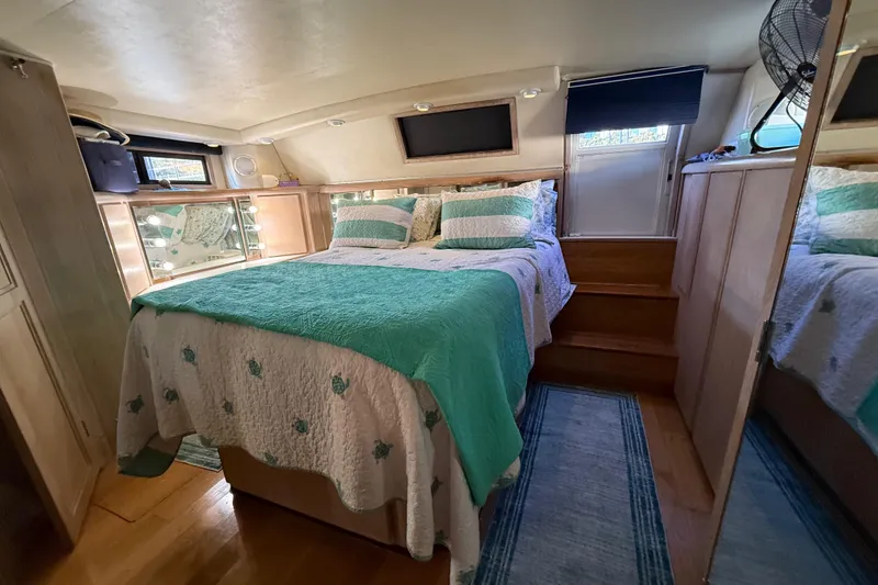 Slide: The Image of Luxurious bedroom in 1991 Californian 55 Cockpit Motor Yacht with teal bedding and wood accents. - 52