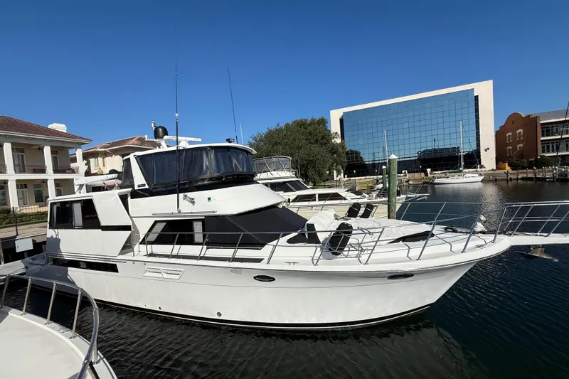Slide: The Image of 1991 Californian 55 Cockpit Motor Yacht docked in marina, modern buildings in background. - 6