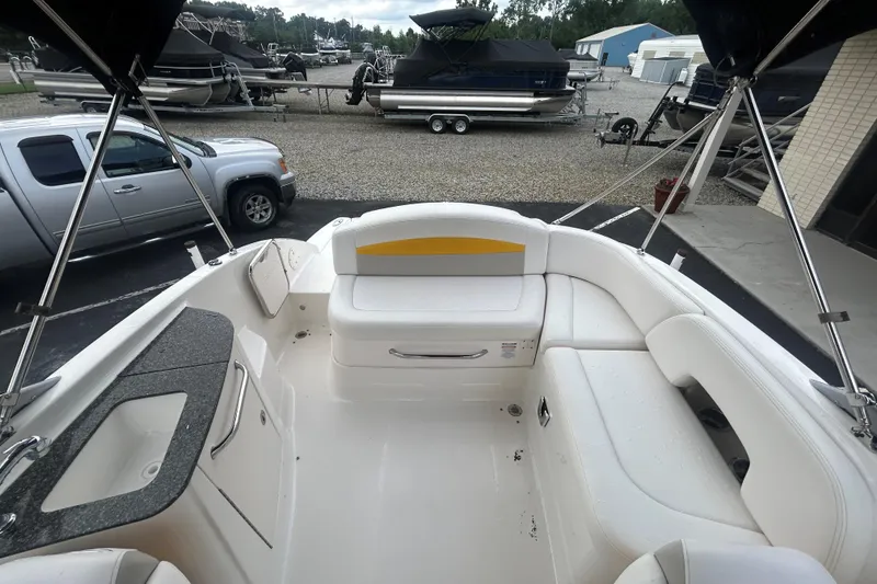Slide: The Image of 2008 Chaparral Sunesta 244 boat interior with white seating and sink, parked near vehicles. - 13
