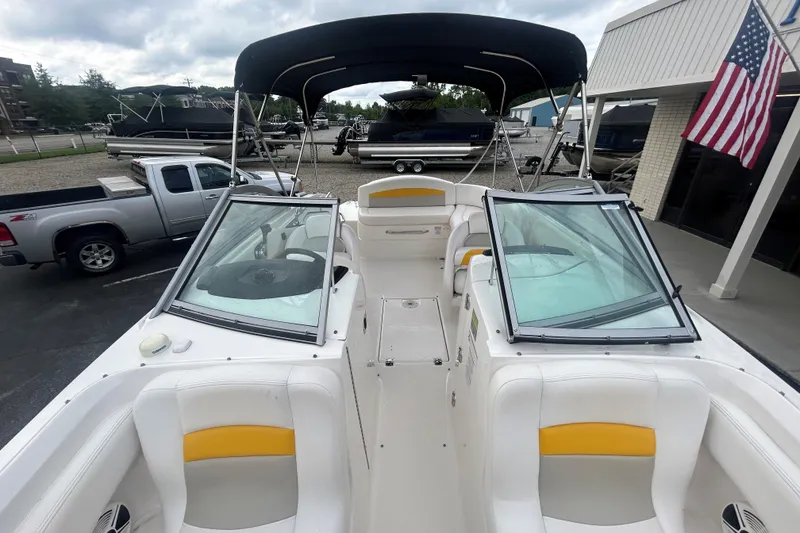 Slide: The Image of 2008 Chaparral Sunesta 244 boat interior with seating, windshield, and canopy in a dealership lot. - 18