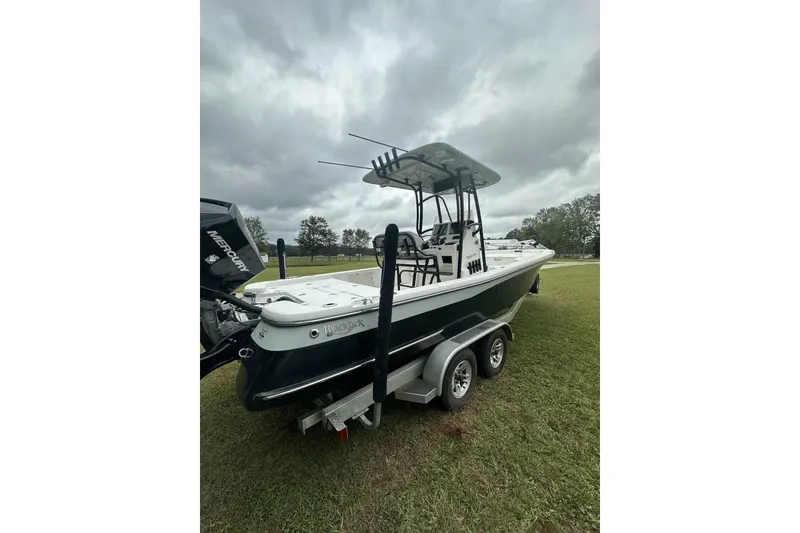 Slide: The Image of 2022 BlackJack 256 Bay boat on trailer, parked on grass under cloudy sky. - 2