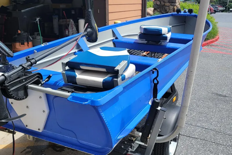 Slide: The Image of 1966 Sea Nymph V-14 blue boat with motor and seating, parked on a trailer. - 4