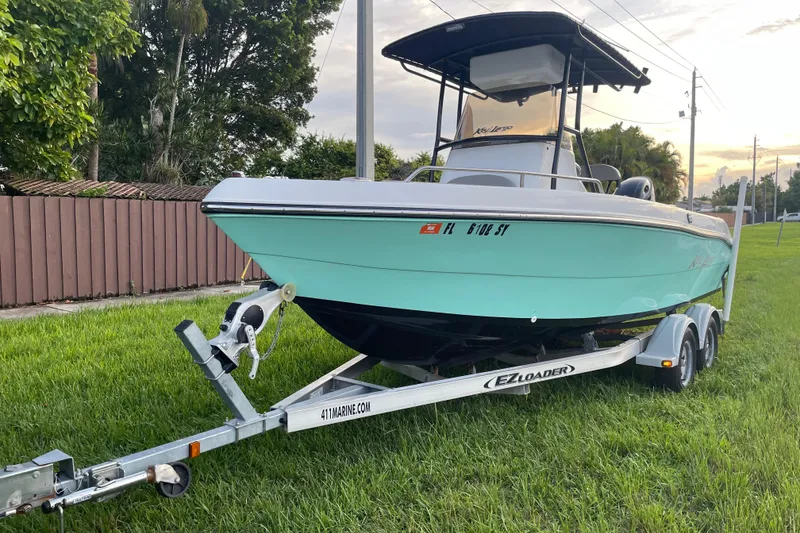 The Image of 2019 Key Largo 2100 CCW boat on trailer, parked on grass, with trees in background. - 0
