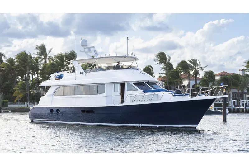 The Image of 2002 Hatteras Motor Yacht on water, palm trees in background, partly cloudy sky. - 0