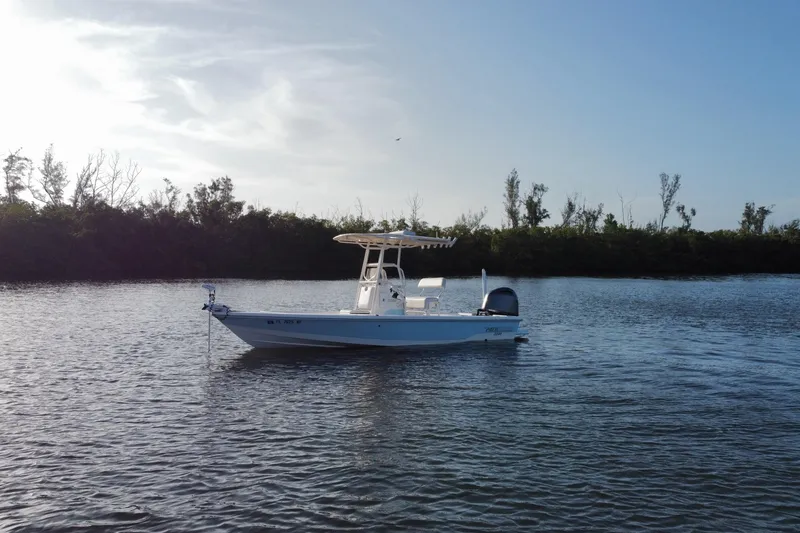 Slide: The Image of 2017 Pathfinder 2200 TRS boat on calm water with tree-lined shore in background. - 8