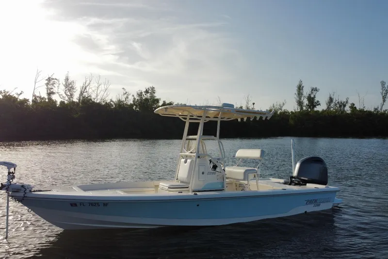 Slide: The Image of 2017 Pathfinder 2200 TRS boat on calm water, surrounded by trees under a clear sky. - 9