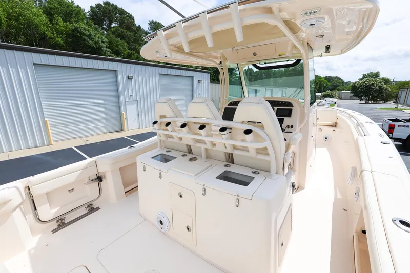 Slide: The Image of 2020 Grady-White Canyon 336 boat interior with seating and storage, docked near industrial buildings. - 13