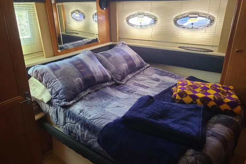 Slide: The Image of Cozy bedroom in 2003 Carver 356 Aft Cabin Motor Yacht with plush bedding and porthole windows. - 9