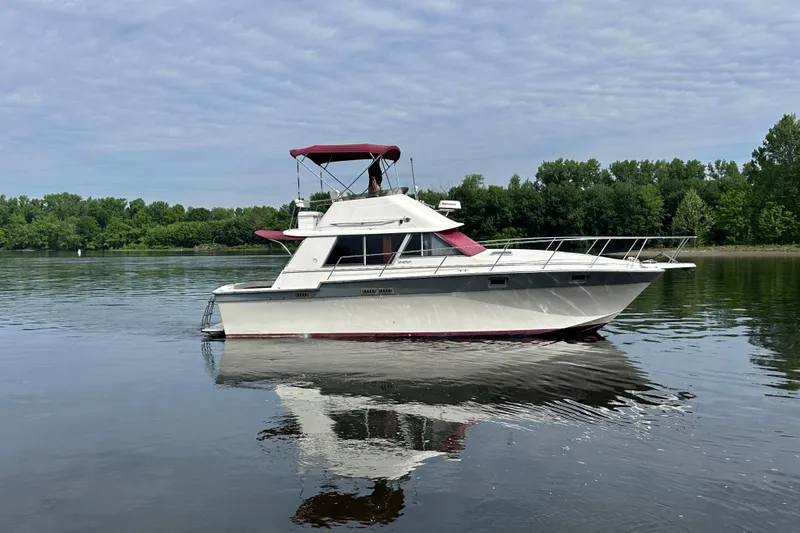 Slide: The Image of 1988 Silverton 34 Convertible boat on calm water with lush green shoreline. - 3