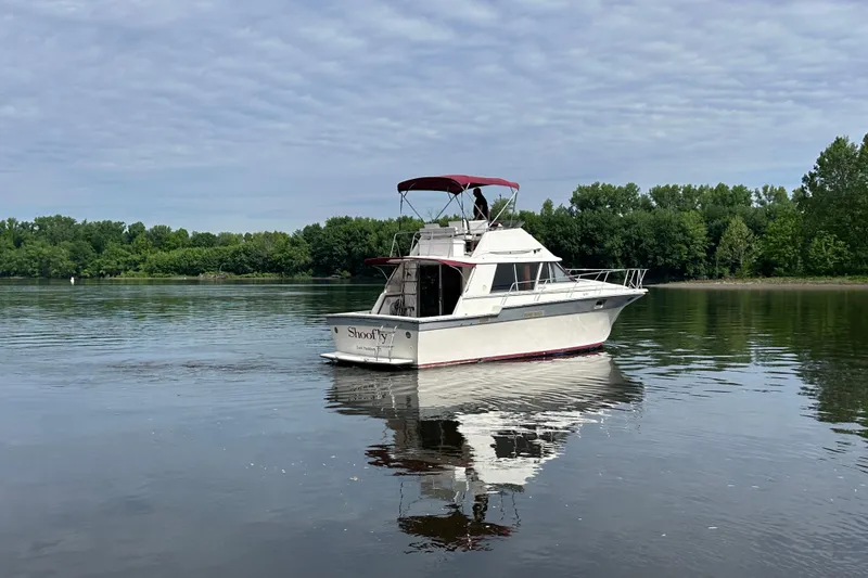 Slide: The Image of 1988 Silverton 34 Convertible boat on calm lake with lush green shoreline. - 4