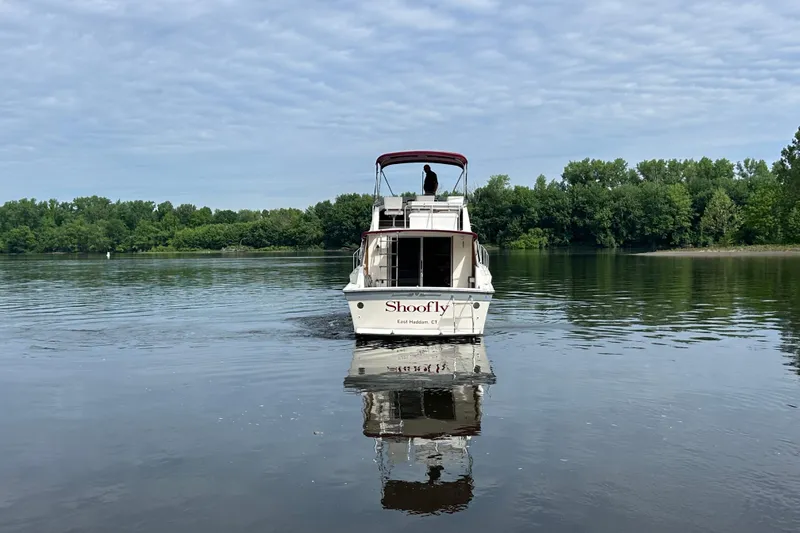 Slide: The Image of 1988 Silverton 34 Convertible boat on calm lake with lush green shoreline. - 5