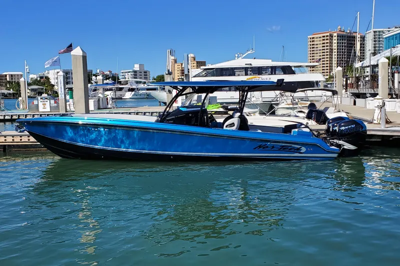 Slide: The Image of 2021 Nor-Tech 340 Sport Center Console boat docked in a marina, blue hull, sunny day. - 6