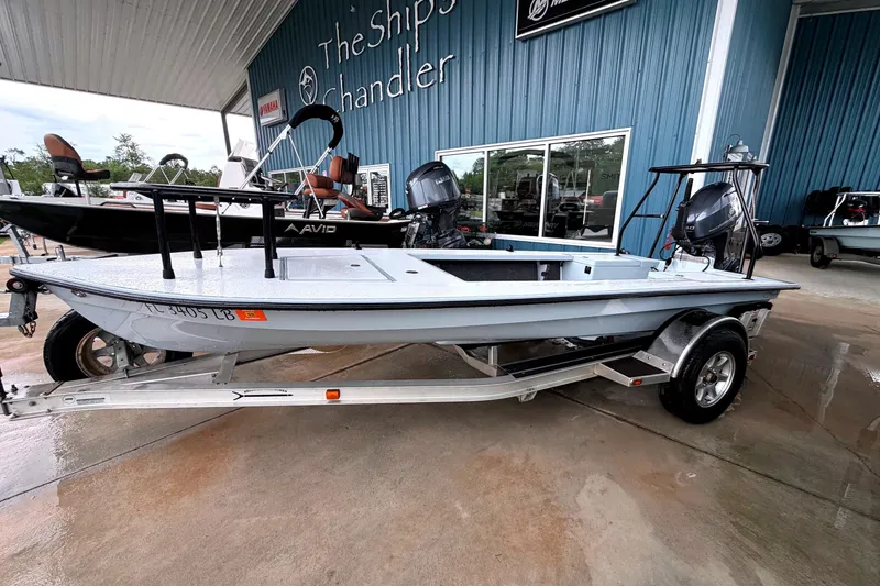 The Image of 1999 Hell's Bay boat on trailer at dealership, featuring sleek design and modern outboard motor. - 1
