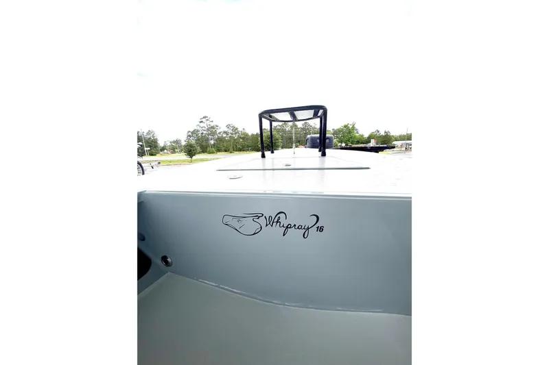 Slide: The Image of 1999 Hell's Bay boat with Whipray 16 logo, parked outdoors. - 5