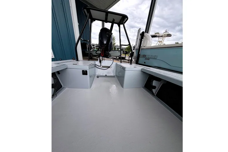 Slide: The Image of 1999 Hell's Bay boat interior with clean deck and motor, docked beside a blue building. - 6