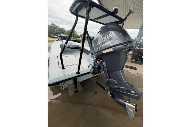 Slide: The Image of 1999 Hell's Bay boat with Yamaha outboard motor, parked under a shelter. - 8