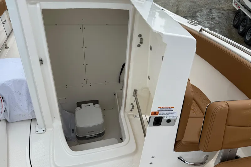 Slide: The Image of 2025 Robalo R232 Explorer boat interior with compact marine toilet and tan seating. - 10