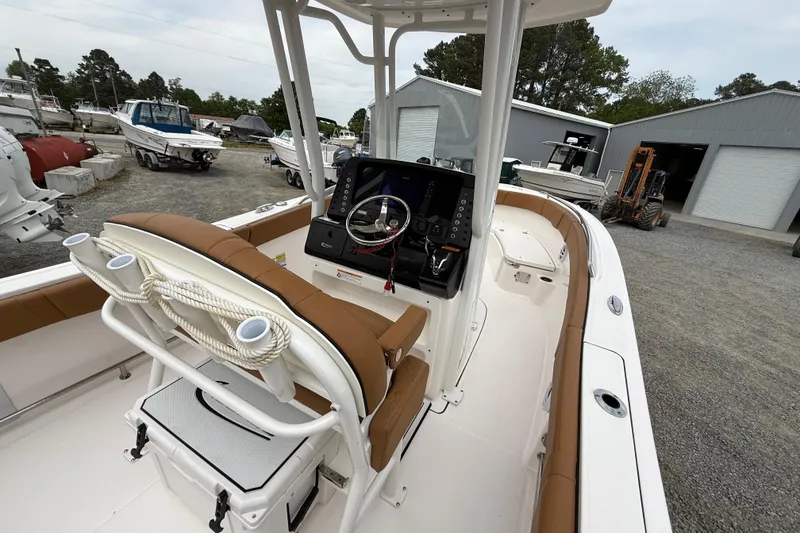 Slide: The Image of 2025 Robalo R232 Explorer boat interior with helm, seating, and storage in a marina setting. - 16