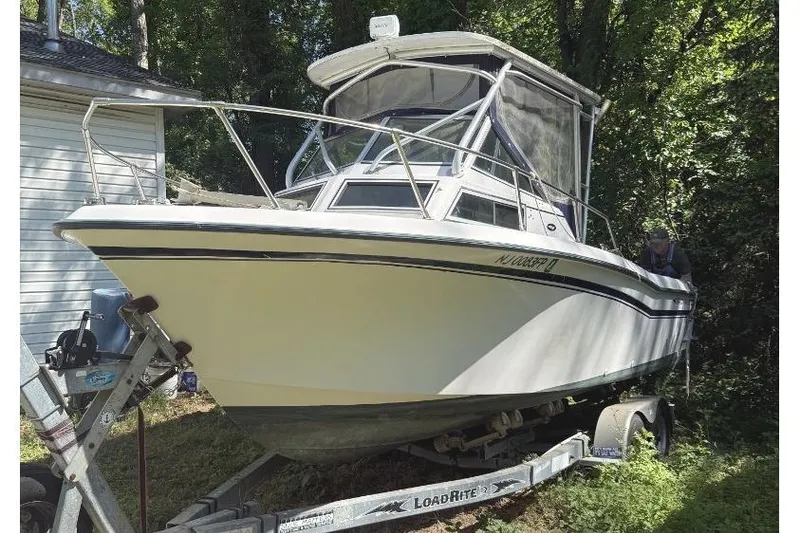 Slide: The Image of 1987 Grady-White Seafarer 226 boat on trailer, parked near a house. - 3