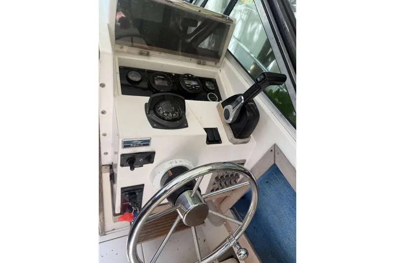 Slide: The Image of 1987 Grady-White Seafarer 226 boat dashboard with steering wheel and controls. - 8