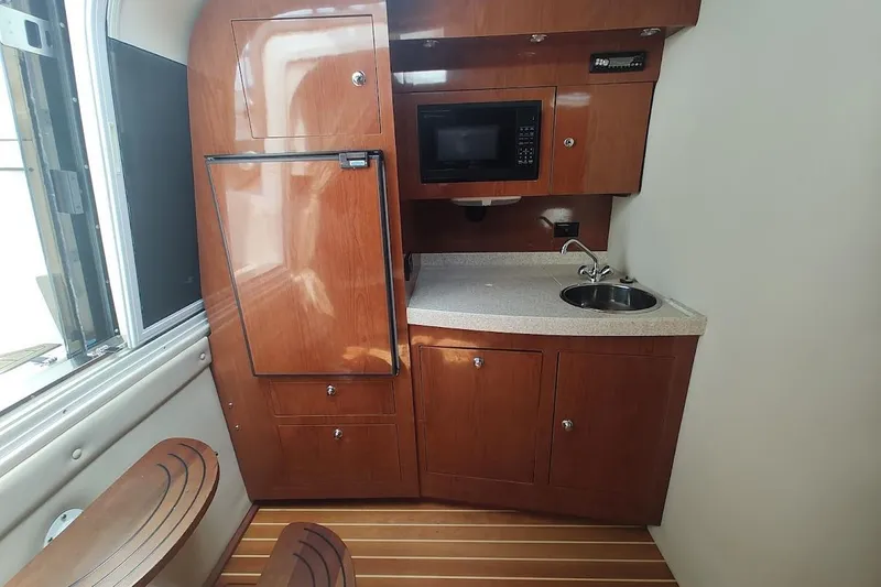 Slide: The Image of 2006 Regal Commodore 3560 IO yacht interior with kitchenette, featuring wood cabinetry and modern appliances. - 20