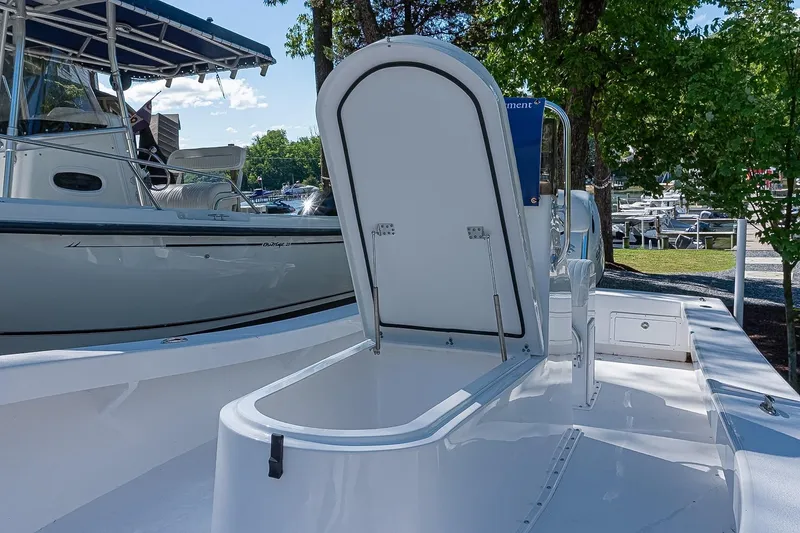 Slide: The Image of 2026 Privateer 2100 Roamer boat with open storage compartment, docked near trees. - 12
