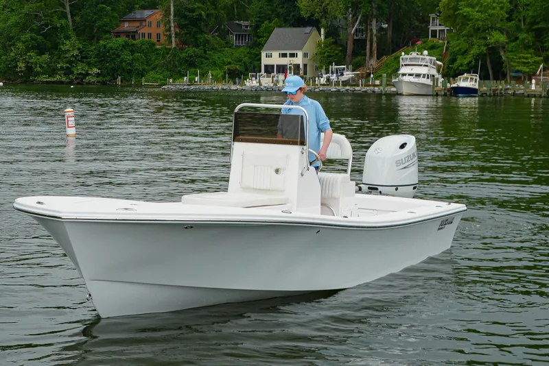 Slide: The Image of 2026 Privateer 2100 Roamer boat cruising on a scenic lake with lush greenery. - 2