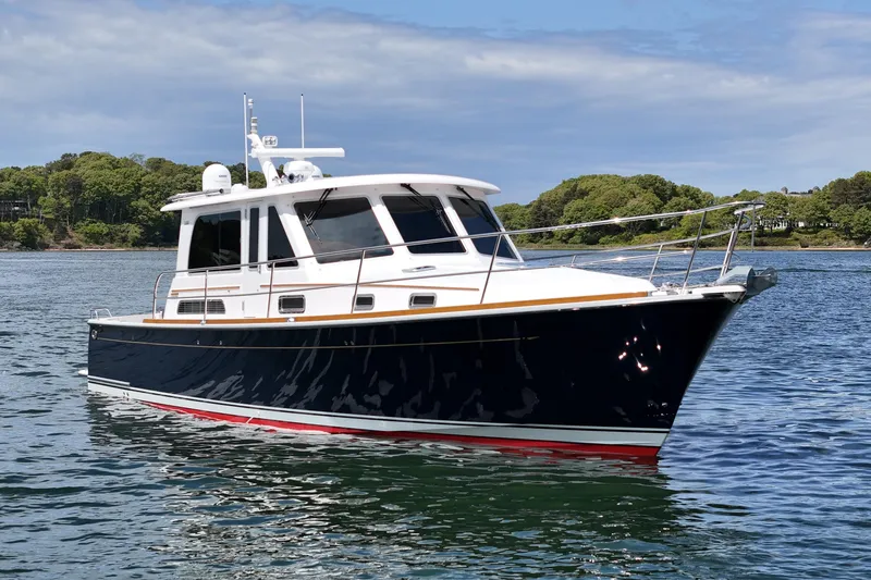 Slide: The Image of 2015 Sabre 42 Salon Express yacht on calm water, surrounded by lush greenery. - 10