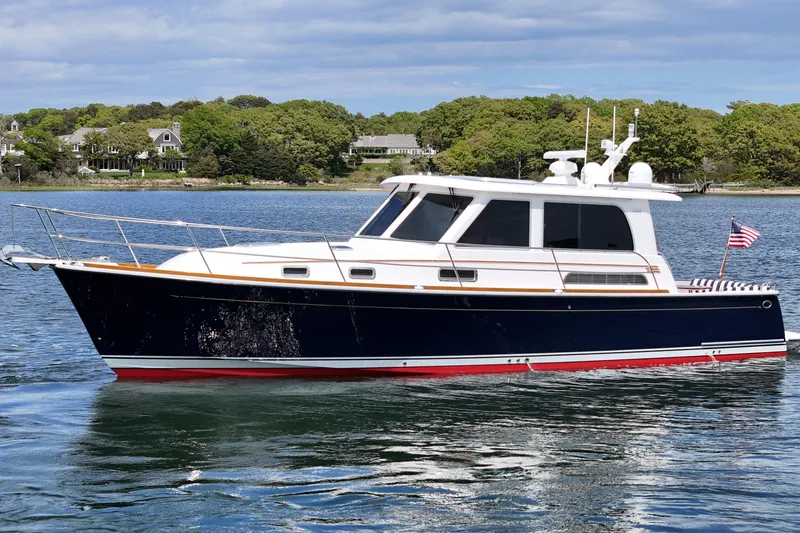 Slide: The Image of 2015 Sabre 42 Salon Express yacht cruising on a scenic lake with lush greenery. - 11