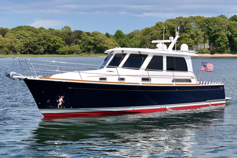 Slide: The Image of 2015 Sabre 42 Salon Express yacht on calm water with lush green shoreline. - 12