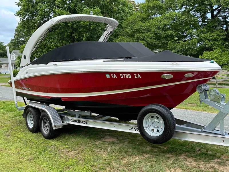 Slide: The Image of 2019 Regal 2000 ES Bowrider on trailer, red and white, covered, parked on grass. - 2