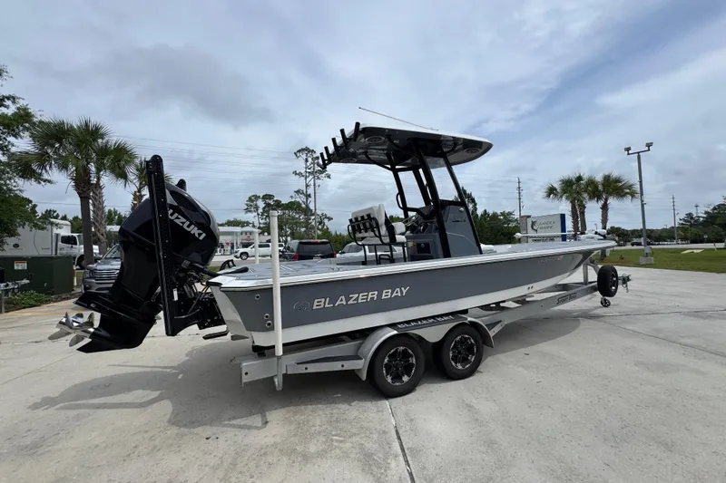 Slide: The Image of 2023 Blazer 2550 GTS boat on trailer, featuring Suzuki outboard motor, parked outdoors. - 11