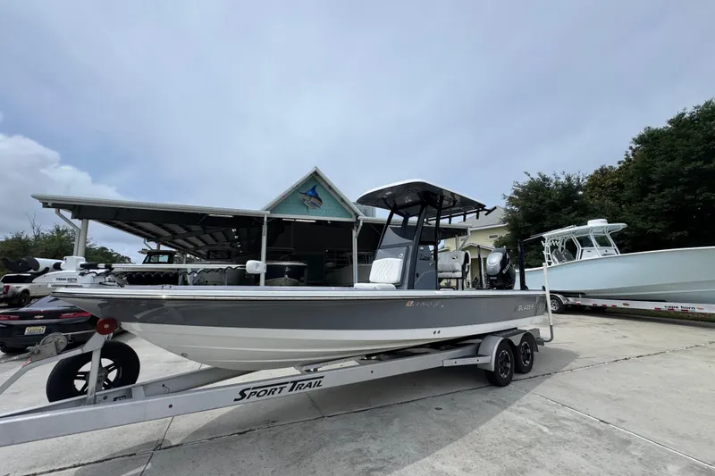 Slide: The Image of 2023 Blazer 2550 GTS boat on trailer, parked outdoors near a covered area. - 3