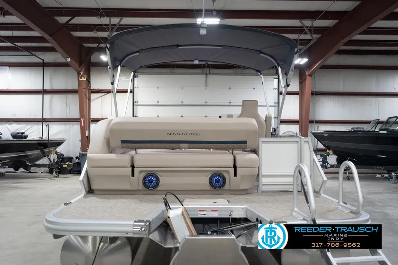 Slide: The Image of 2026 Bennington 22 ML pontoon boat in showroom, featuring beige seating and blue speakers. - 9