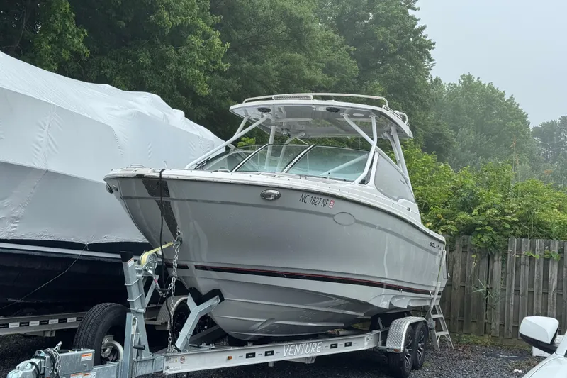 The Image of 2023 Solara S-250 DC boat on trailer, parked outdoors near trees. - 0