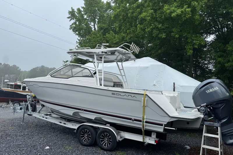 Slide: The Image of 2023 Solara S-250 DC boat on trailer, parked outdoors near trees. - 2