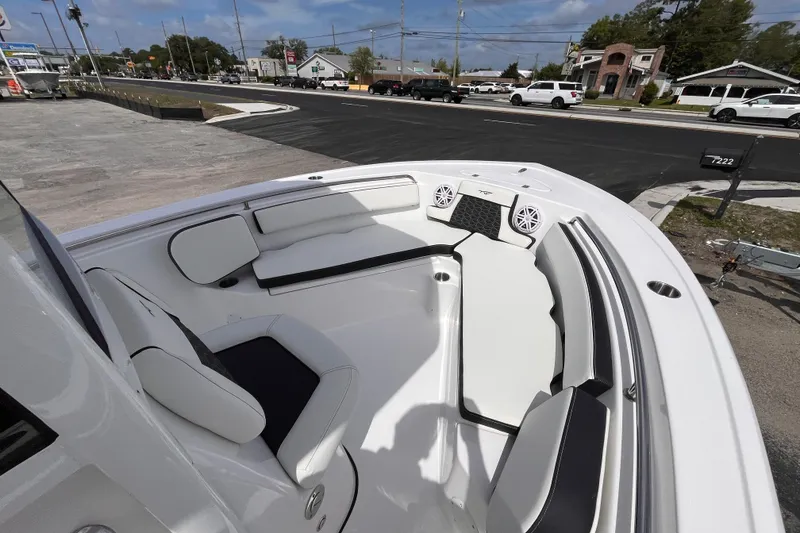 Slide: The Image of 2026 Tidewater 210 LXF boat interior with white seating and speakers, parked near a road. - 9