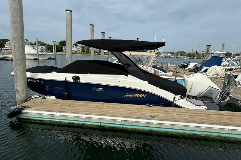 Slide: The Image of 2023 Sea Ray SLX 260 Outboard docked, blue and white design. - 3
