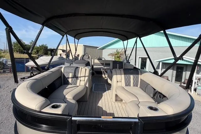 Slide: The Image of 2023 Barletta L23U pontoon boat with spacious seating and canopy, parked outdoors. - 11