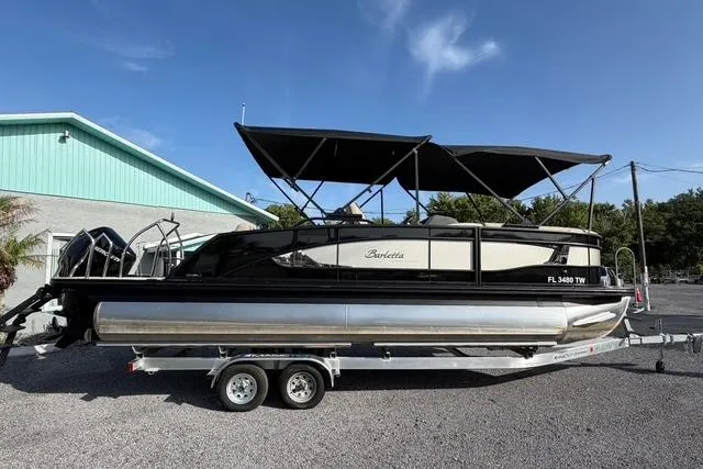 Slide: The Image of 2023 Barletta L23U pontoon boat on trailer, parked outdoors under clear sky. - 3