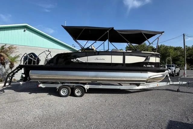 Slide: The Image of 2023 Barletta L23U pontoon boat on trailer, parked outdoors under clear sky. - 5