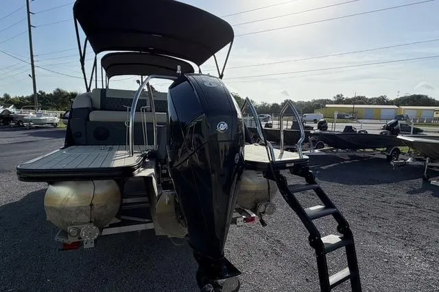 Slide: The Image of 2023 Barletta L23U pontoon boat with outboard motor and ladder, parked outdoors. - 8