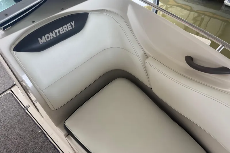 Slide: The Image of 2005 Monterey 248LS Montura Bowrider interior seating with logo, featuring white upholstery. - 21