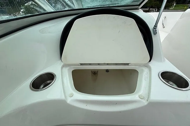 Slide: The Image of 2011 Sea Ray 205 Sport boat dashboard with open storage compartment and cup holders. - 17