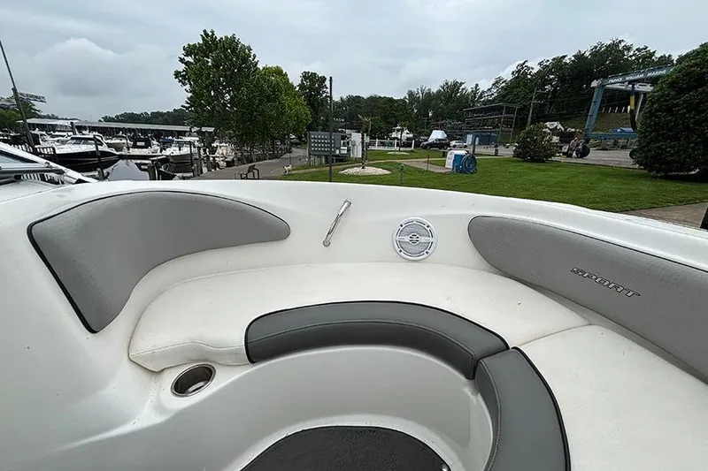 Slide: The Image of 2011 Sea Ray 205 Sport boat interior with cushioned seating, docked at marina. - 21