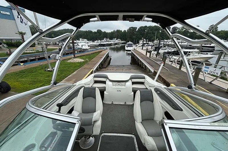 Slide: The Image of 2011 Sea Ray 205 Sport boat interior at marina, showcasing seating and docking area. - 23